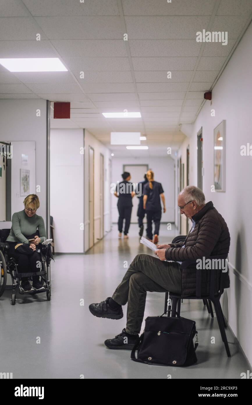 Seitenansicht des älteren männlichen Patienten, der im Wartezimmer im Krankenhaus auf einem Stuhl sitzt Stockfoto