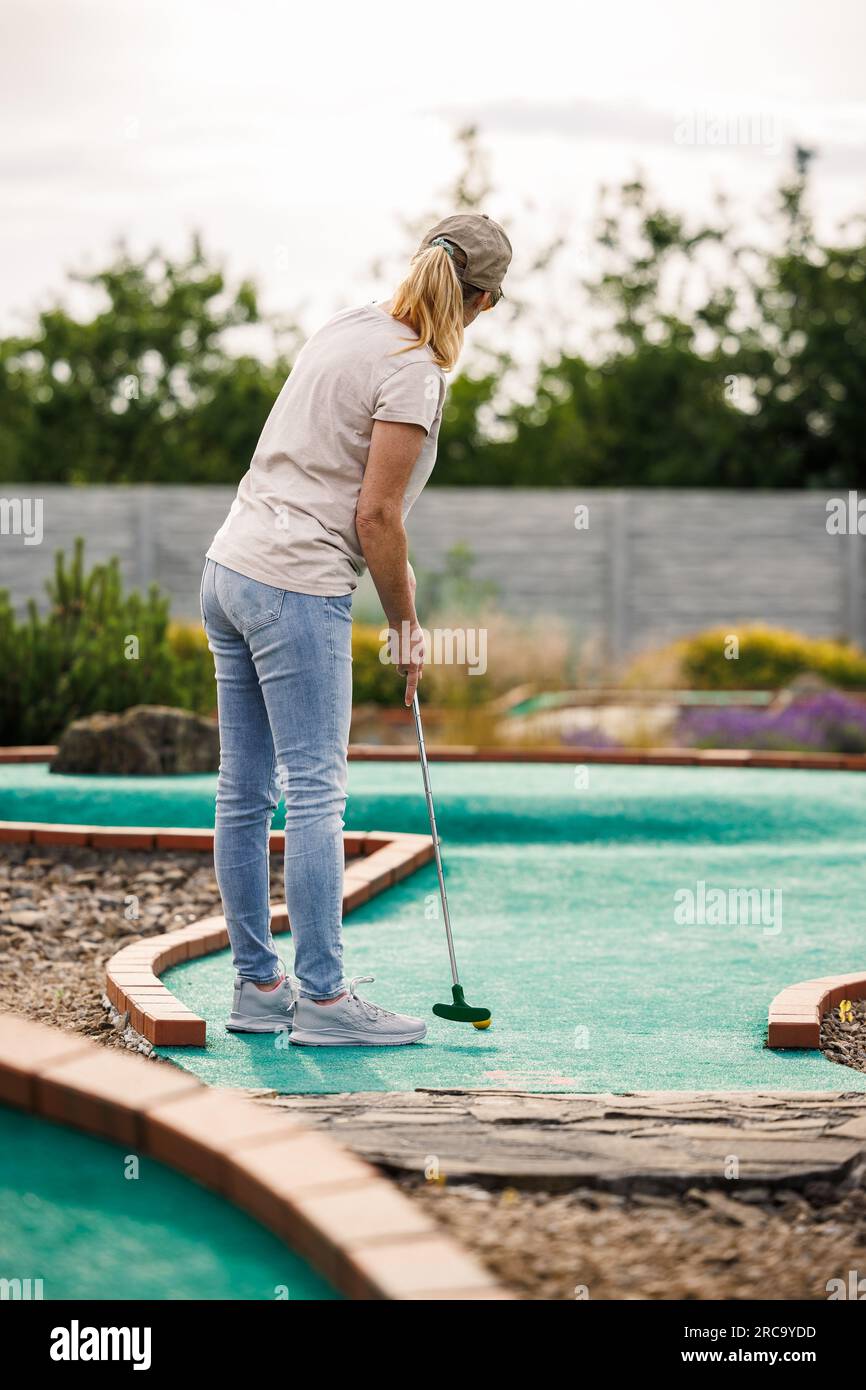 Frau spielt Minigolf auf dem Golfplatz. Sommersport und Freizeitaktivitäten Stockfoto