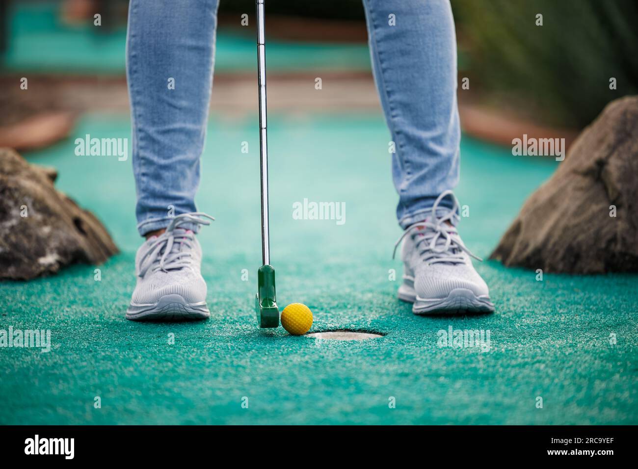 Golfer, der Abenteuer oder Minigolf spielt und versucht, den Ball ins Loch zu stecken. Sommersportaktivität Stockfoto