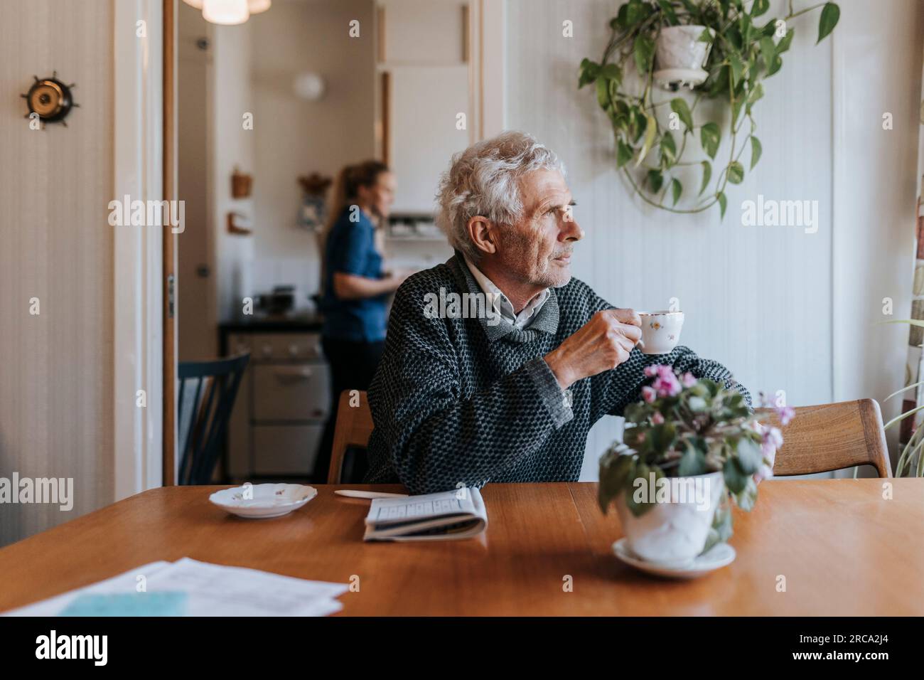 Rücksichtsvoller Senior-Mann, der zu Hause am Esstisch saß und eine Teetasse hielt Stockfoto