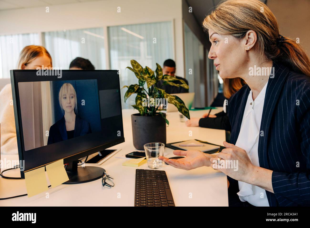 Geschäftsfrau, die mit einem Kollegen am Computer in einer Arbeitsstelle Videoanrufe führt Stockfoto