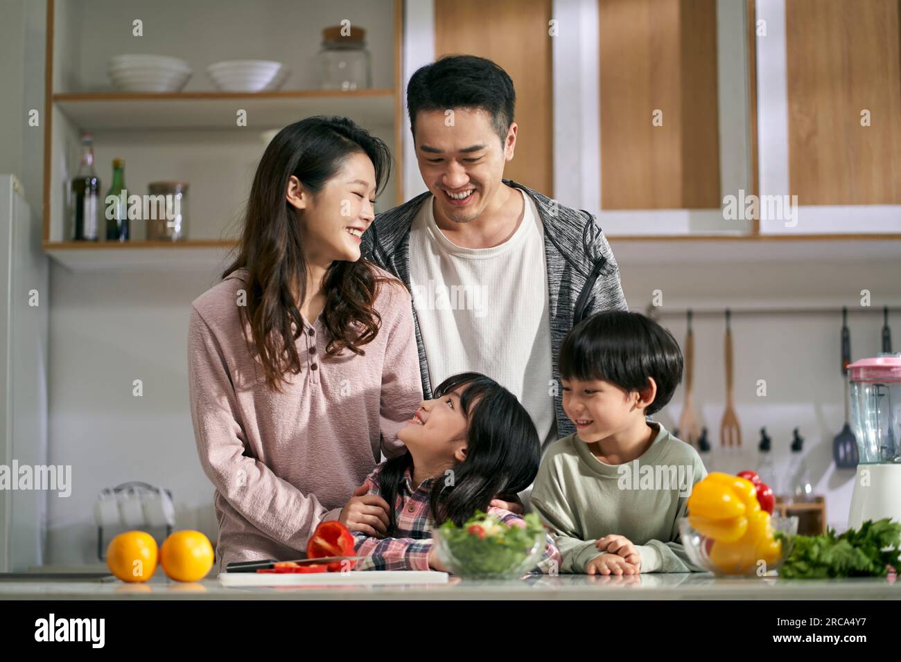Glückliche asiatische Familie mit zwei Kindern, die eine schöne Zeit zusammen in der Küche zu Hause genießen Stockfoto