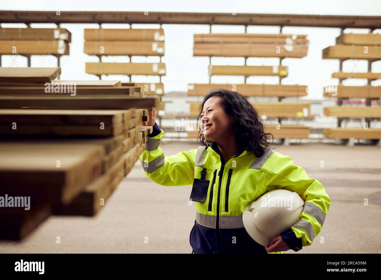 Lächelnde Mitarbeiterin, die Bretter in der Holzindustrie untersucht Stockfoto