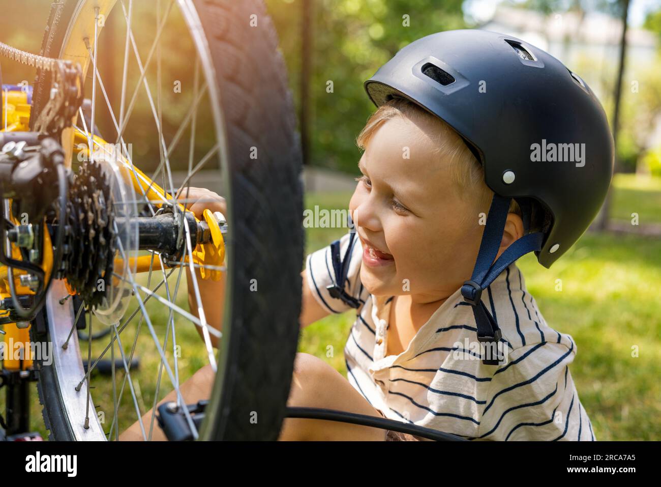 Glückliches kleines Kind, das das Rad mit dem Schraubenschlüssel repariert Stockfoto