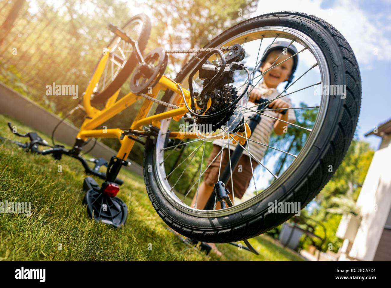 Ein Junge bläst den Fahrradreifen mit einer Luftpumpe auf dem Hinterhof auf. Motorradwartung Stockfoto