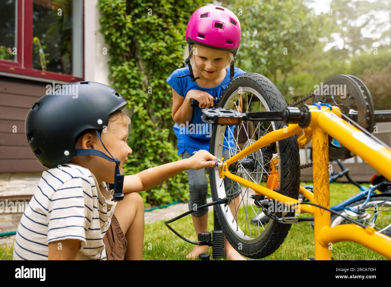 Kinder, die Fahrräder warten und reparieren, im Hinterhof. Fahrradsicherheit Stockfoto