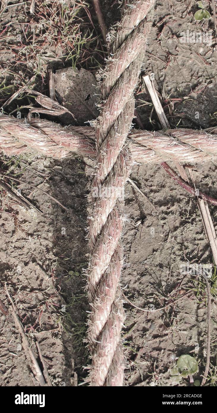 Seil an Seil. Ein Kreuz aus Seilen. Detail eines alten verwitterten Seils auf dem Boden. Stockfoto