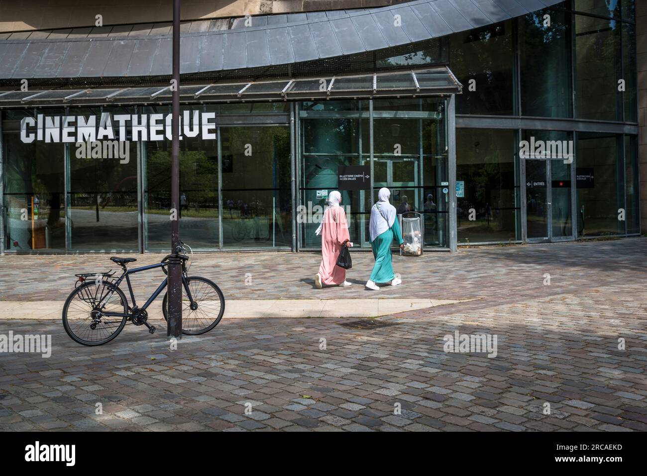 Zwei muslimische Frauen kommen an der Cinémathèque Francise vorbei, einem von Frank Gehry entworfenen Gebäude mit einem Museum und Filmvorführungen. Paris, Frankreich Stockfoto