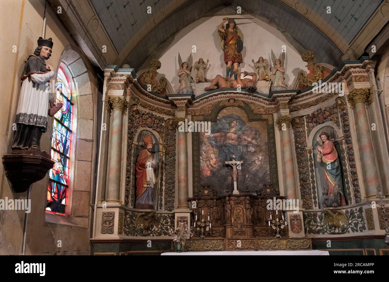 Französischer Barock in der Kirche St. Michaels Erzengel, aus polychromem Holz. Der heilige Michael an der Spitze mit dem gehobenen Schwert, das kurz davor ist, einen Schlag zu versetzen. Der heilige Michael ist kein heiliger, sondern ein Engel und der Anführer aller Engel und der Armee Gottes. Saint Michel en Greve, Cotes-d'Armor, Bretagne, Frankreich. 10. Juli 2023 2020s HOMER SYKES Stockfoto