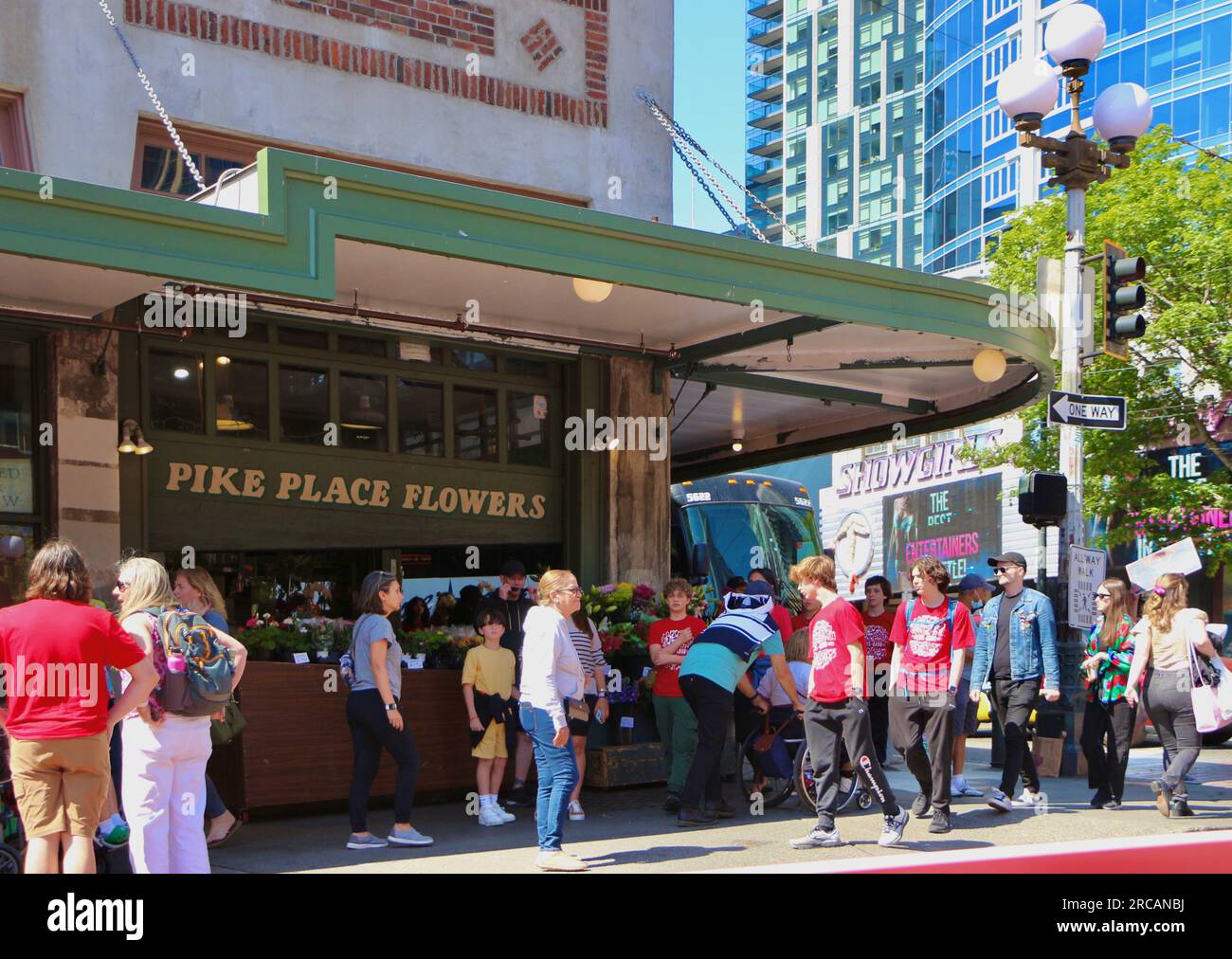 Familiengeführter Pike Place Flowers Shop an der Ecke von First und Pike mit vorbeifahrenden Touristen an einem geschäftigen sonnigen Nachmittag Seattle Washington State USA Stockfoto