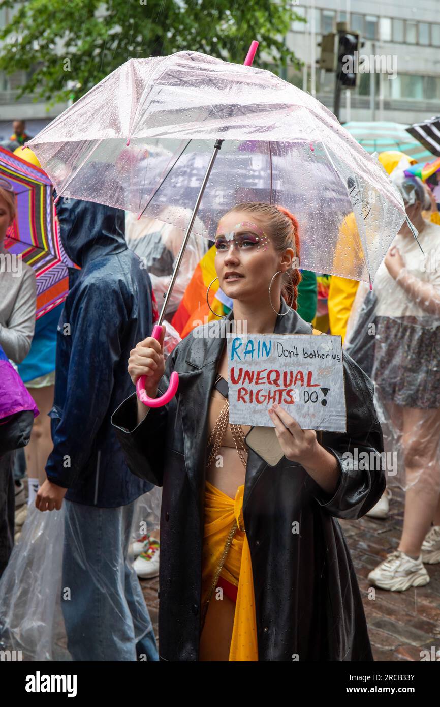 Regen stört uns nicht, ungleiche Rechte tun es! Junge Frau mit handgemachtem Schild und durchsichtigem Regenschirm auf der Helsinki Pride 2023 Parade. Stockfoto