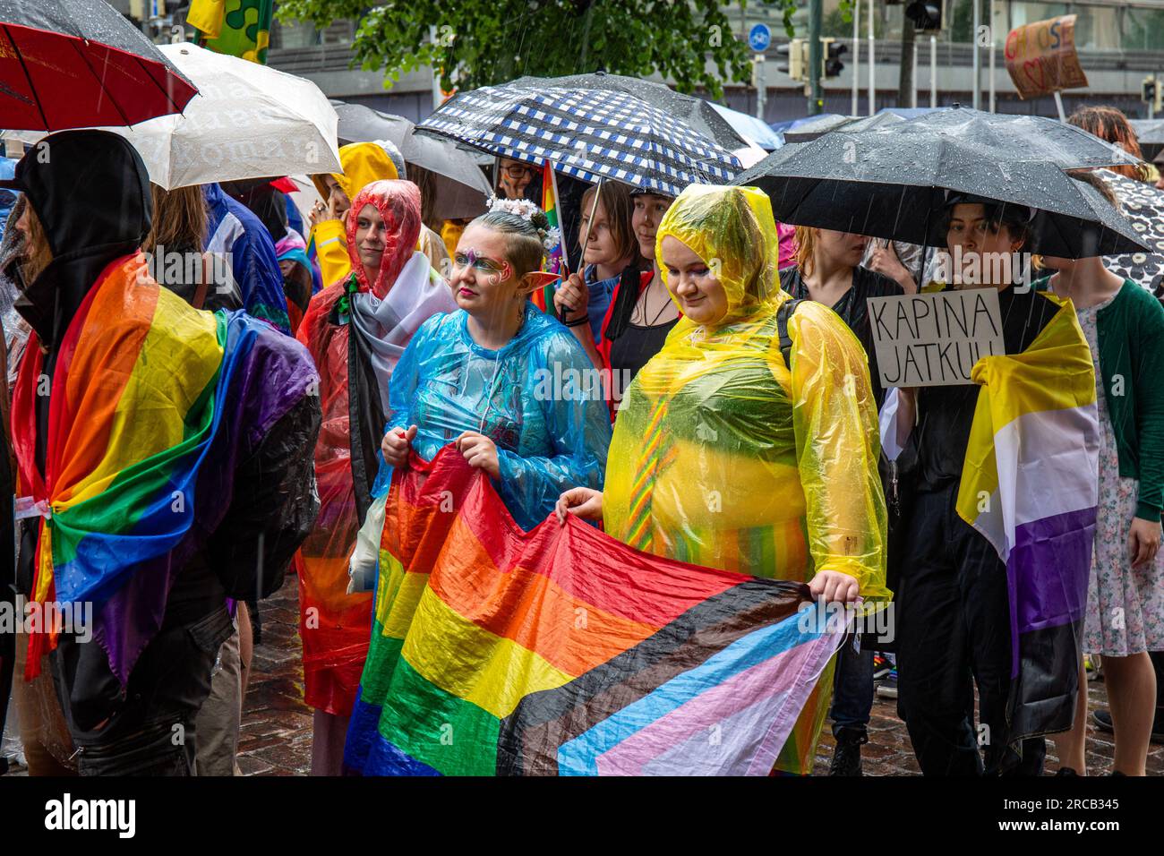 Teilnehmer mit Schirmen und Einweg-Regenmänteln bei der Helsinki Pride 2023 Parade an Regentagen in Helsinki, Finnland Stockfoto