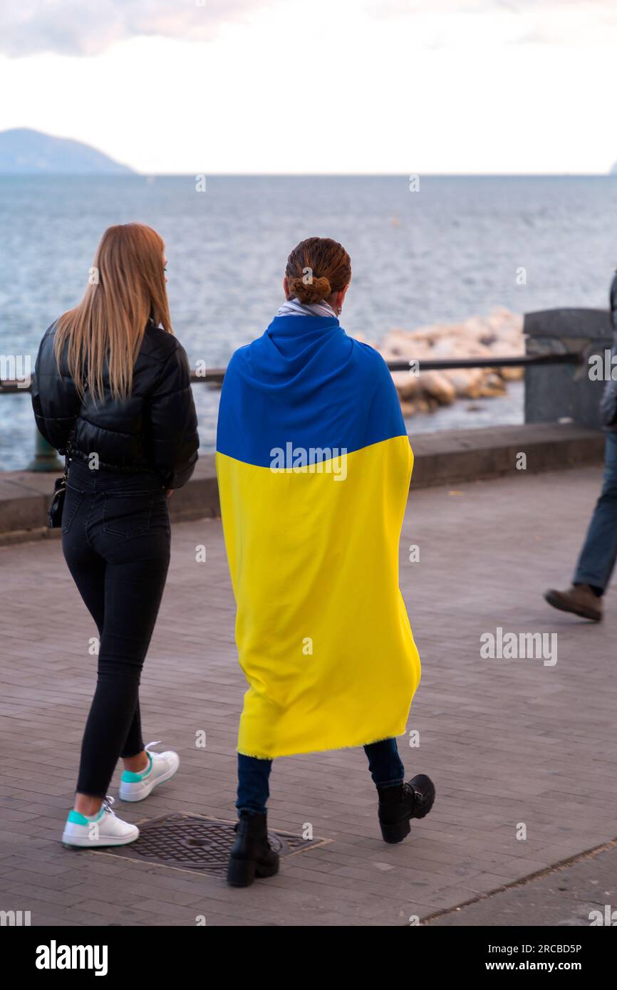 Zivilisten, die die Ukraine beim Konflikt mit Russland im Jahr 2022 unterstützen und die ukrainische Staatsflagge außerhalb von Neapel, Italien, anbinden. Stockfoto