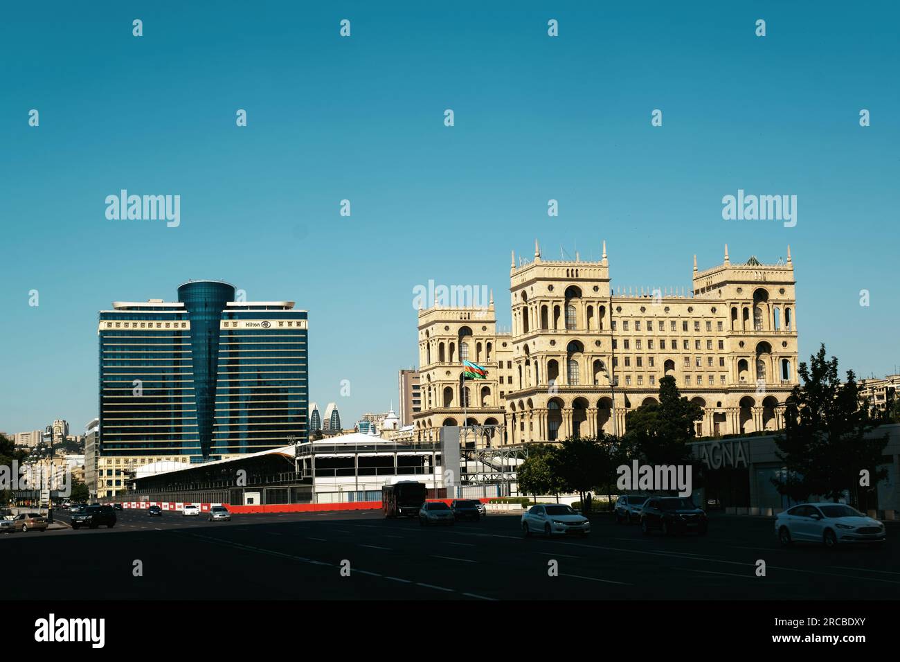 Baku, Aserbaidschan - 26. Juni 2023: Ein eindrucksvolles Bild, das in der Morgendämmerung mit dem historischen Regierungsgebäude neben dem zeitgenössischen Hilton Hotel, Pres Stockfoto