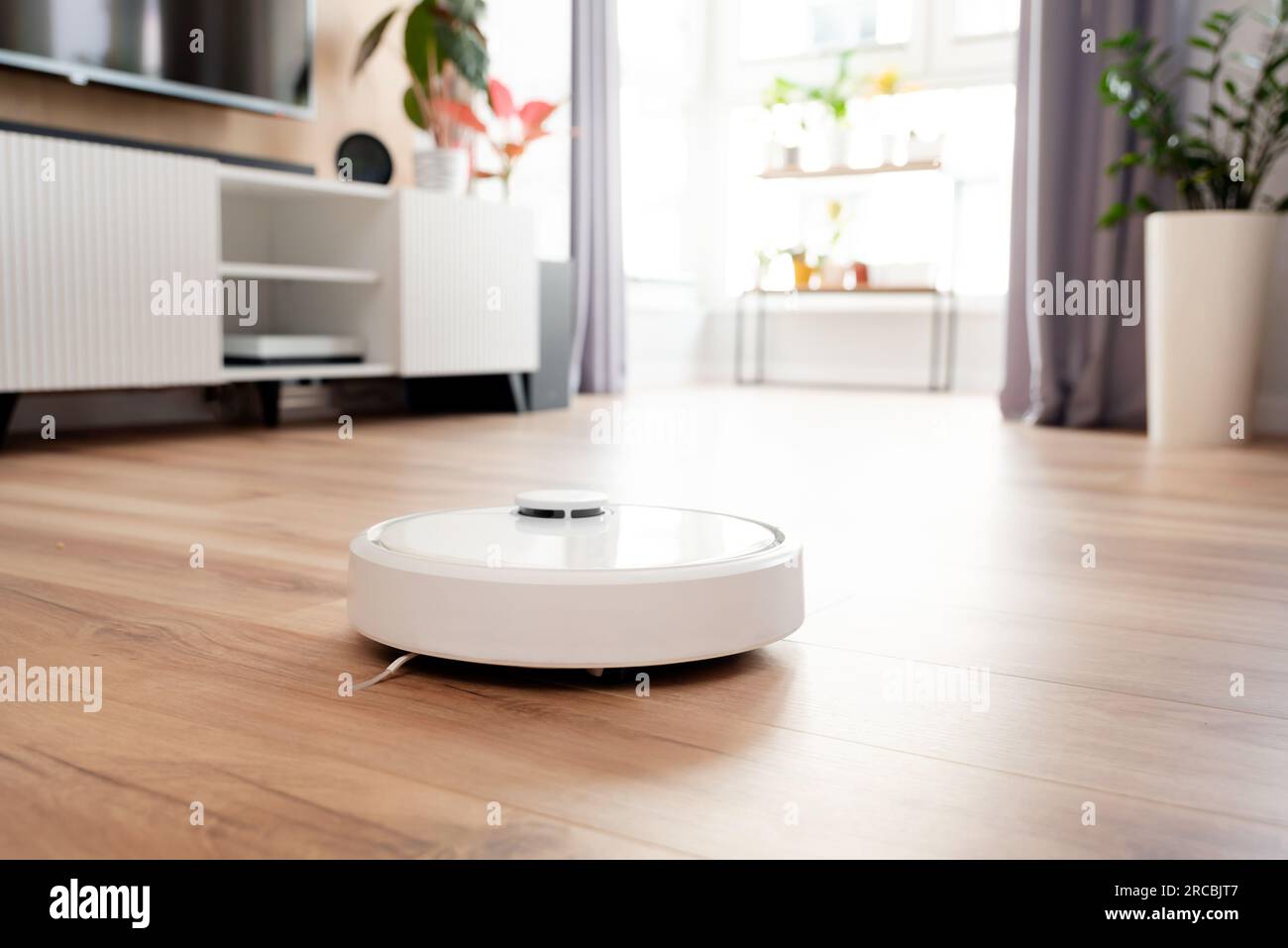 Weißer Roboter-Staubsauger auf dem Boden im Wohnzimmer, Smart-Home-Gerät Stockfoto