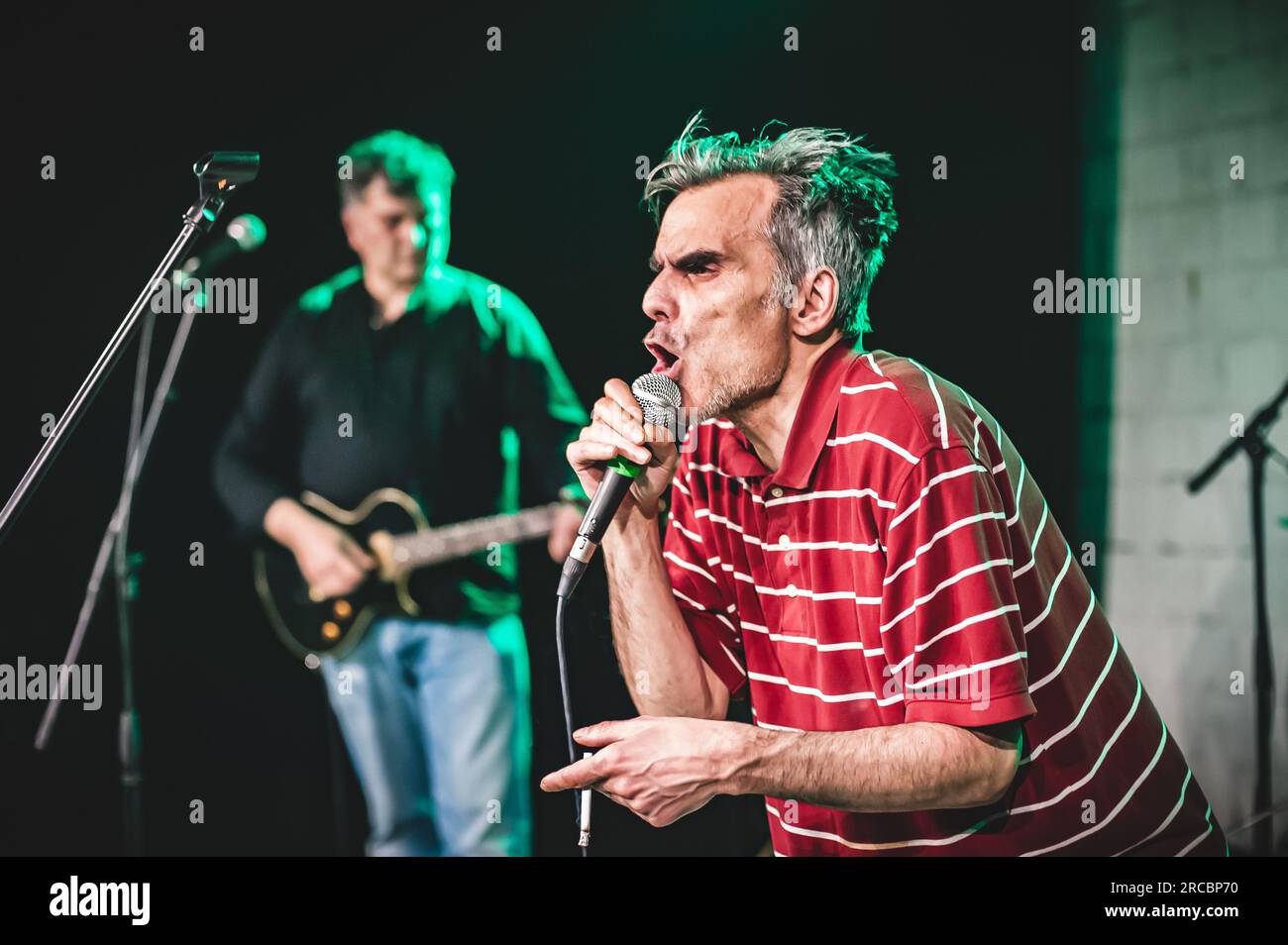 Der Sänger, der Künstler ist, nimmt während einer Live-Aufführung auf einer Bühne ein Porträt auf. Punk-Rock-Musikband-Gruppe Stockfoto