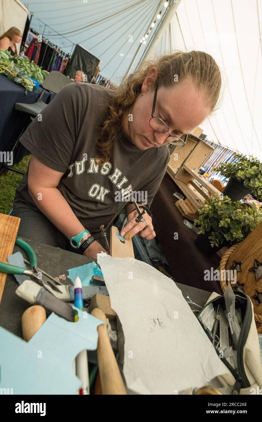 Handwerker, der mit einer Handsäge arbeitet und ein Design auf einem Silberstück aus einem Papierdesign ausschneidet. Stockfoto