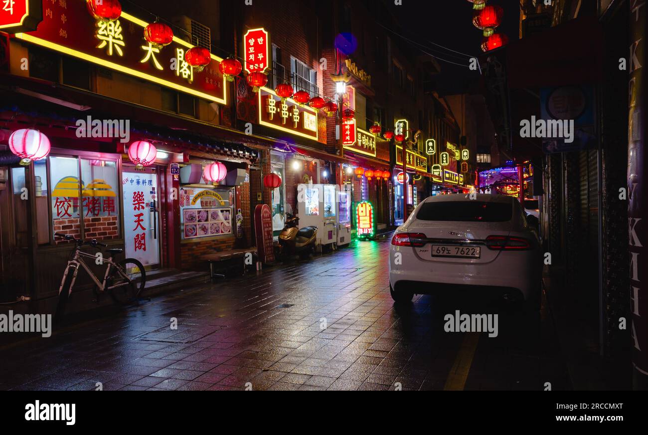 Busan, Südkorea - 19. März 2018: Nachtsicht auf die Straße mit farbenfroher Neonwerbung, Fahrräder und Autos werden auf der Straße in der Innenstadt geparkt Stockfoto