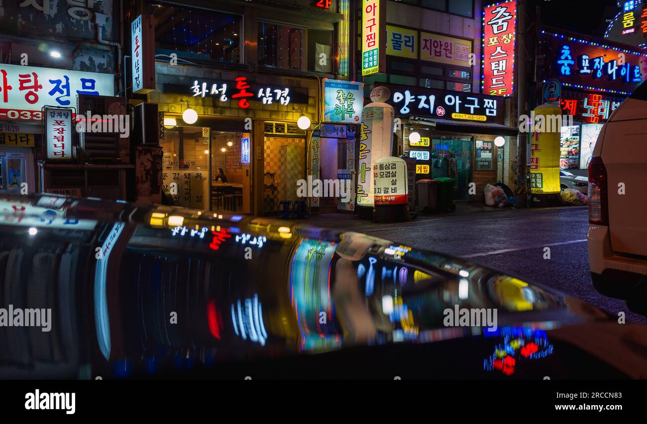 Busan, Südkorea - 19. März 2018: Nachtsicht auf die Straße mit farbenfroher Neonwerbung und Reflexionen Stockfoto