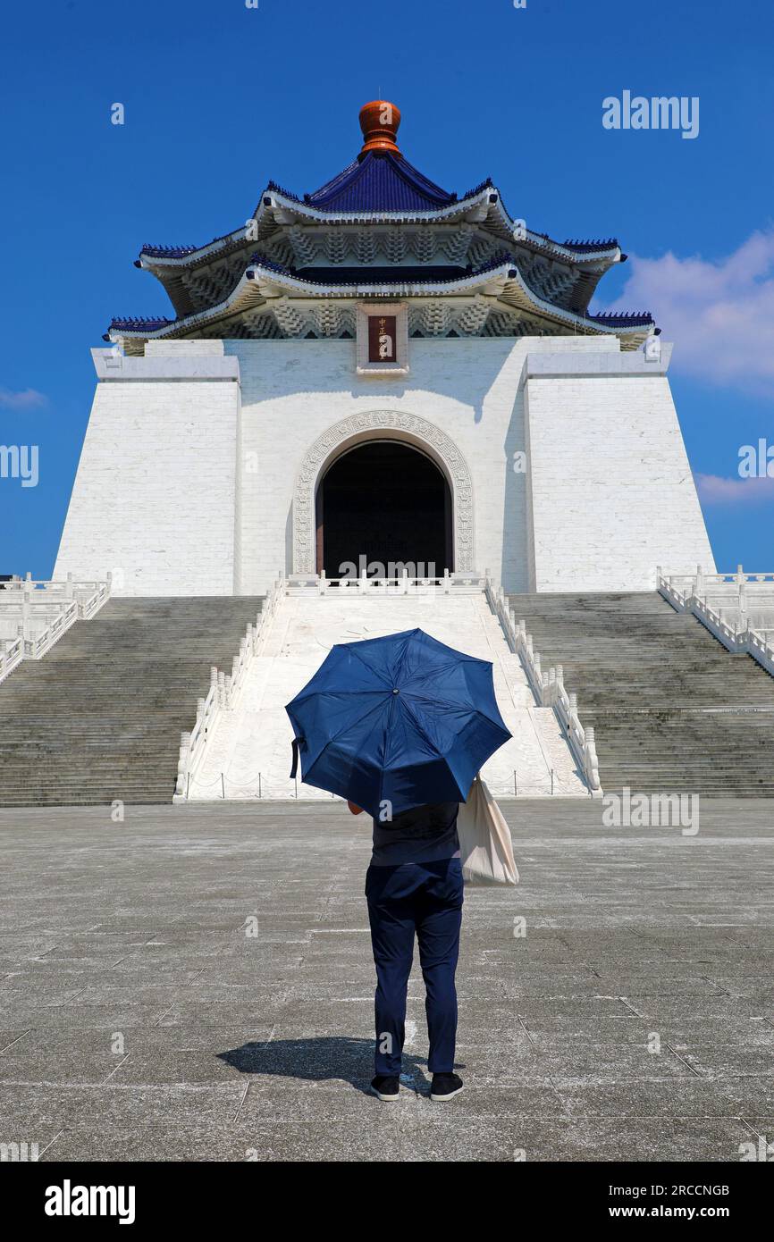 Mann mit blauem Regenschirm vor der National Chiang Kai-Shek Memorial Hall, Memorial Hall Square, Taipei, Taiwan Stockfoto