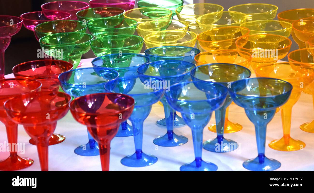 Große Auswahl an bunten Trinkgläsern für eine Party auf einem Tisch. Stockfoto