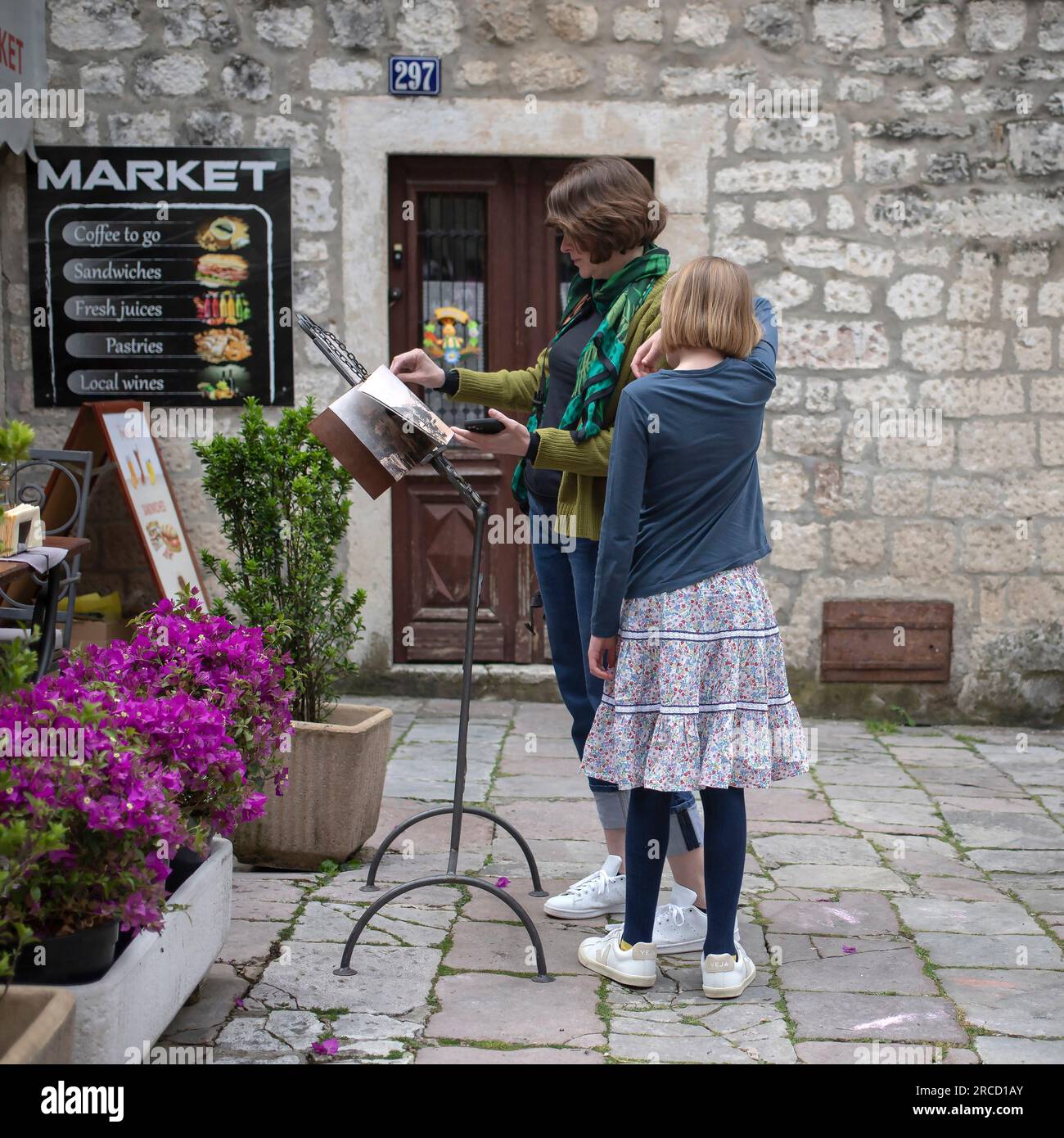 Kotor, Montenegro, 13. April 2023: Frau mit einer Tochter, die in der Altstadt ein Restaurantmenü durchsucht Stockfoto