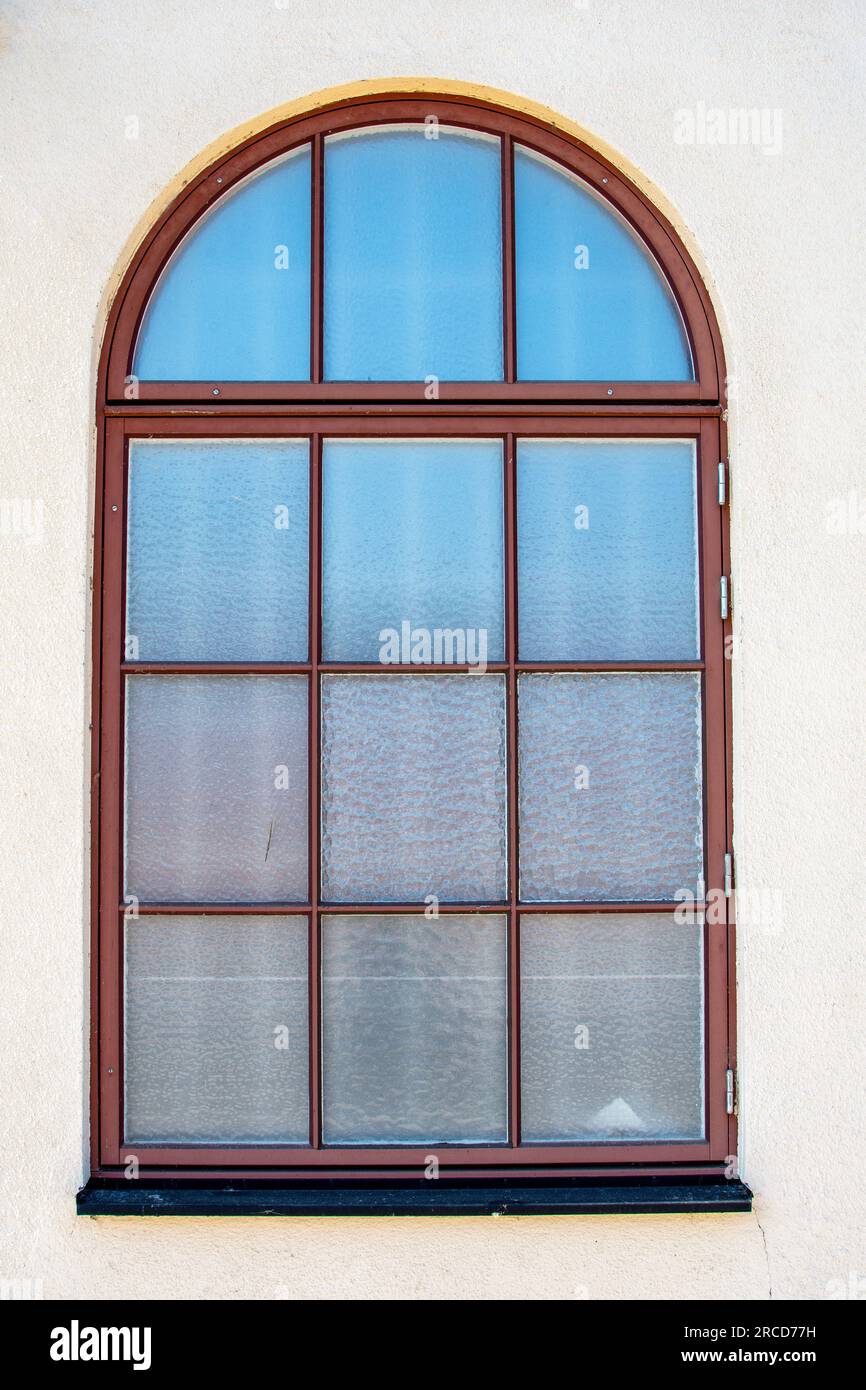 Antikes rotes Bogenfenster, das den blauen Himmel in Milchglas reflektiert Stockfoto