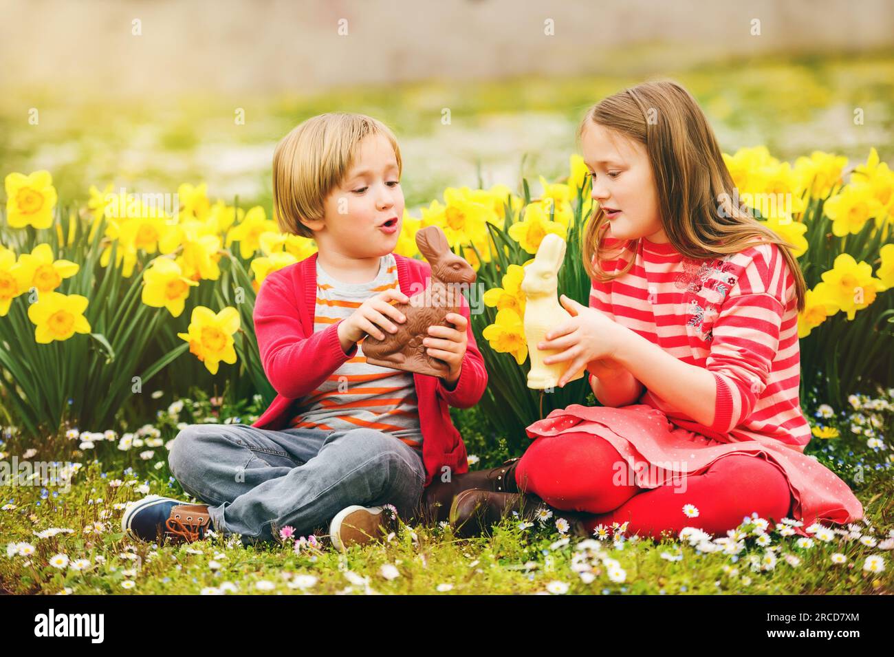 Süße kleine Kinder, große Schwester und kleiner Bruder, mit Schokoladen-Osterhasen, die ein traditionelles Festmahl feiern. Familie, Urlaub, Frühling, sorgenfreies Kind Stockfoto