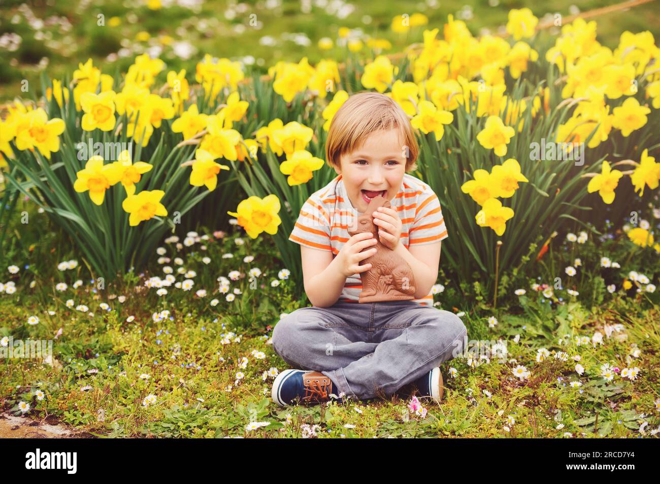 Süßer kleiner Junge mit Schokoladen-Osterhasen, der ein traditionelles Festmahl feiert. Familie, Urlaub, Frühling, sorgenfreies Kindheitskonzept. Stockfoto