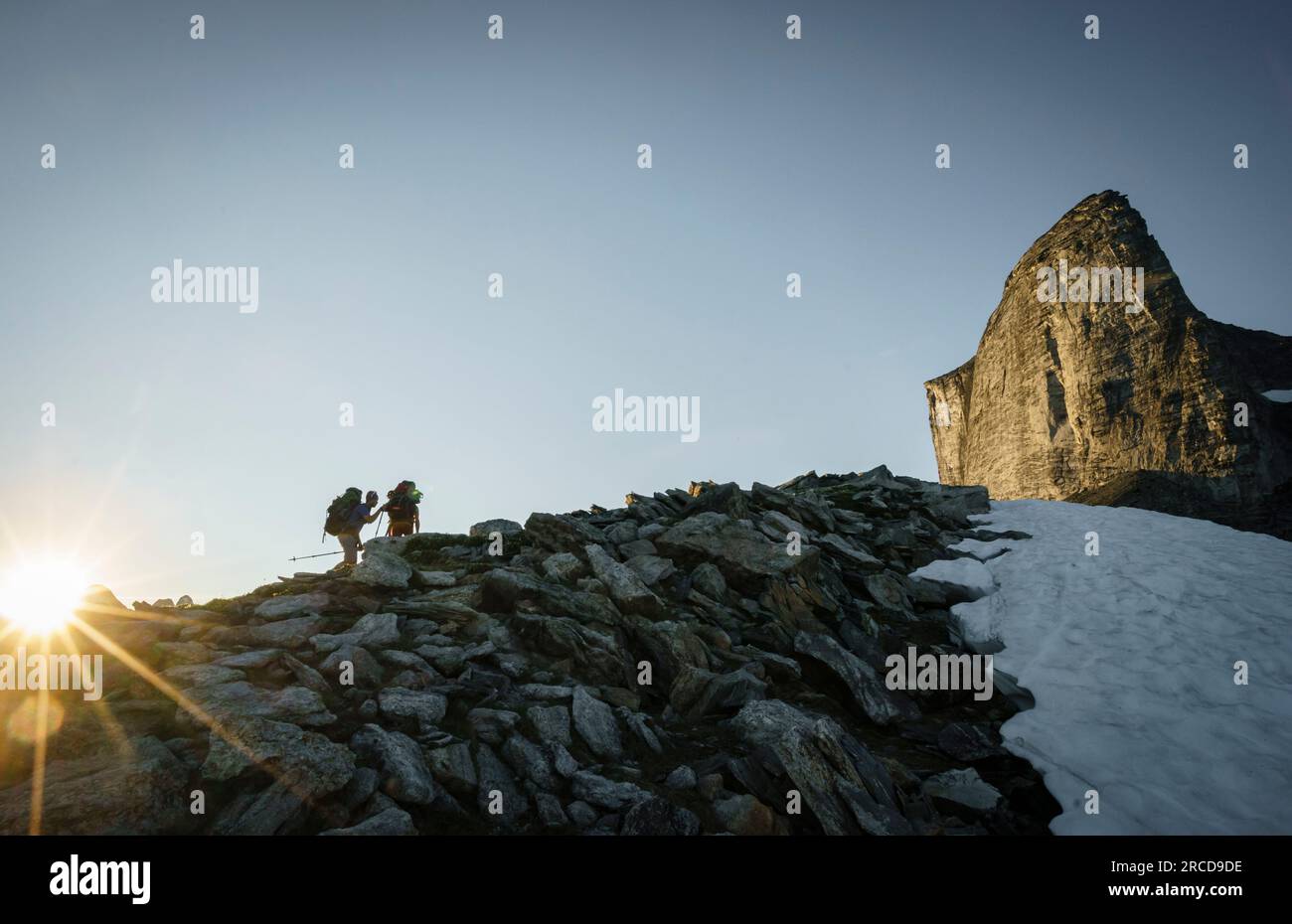 Zwei Wanderer nähern sich dem sonnigen Berg bei Sonnenuntergang über Felsen, BC Stockfoto
