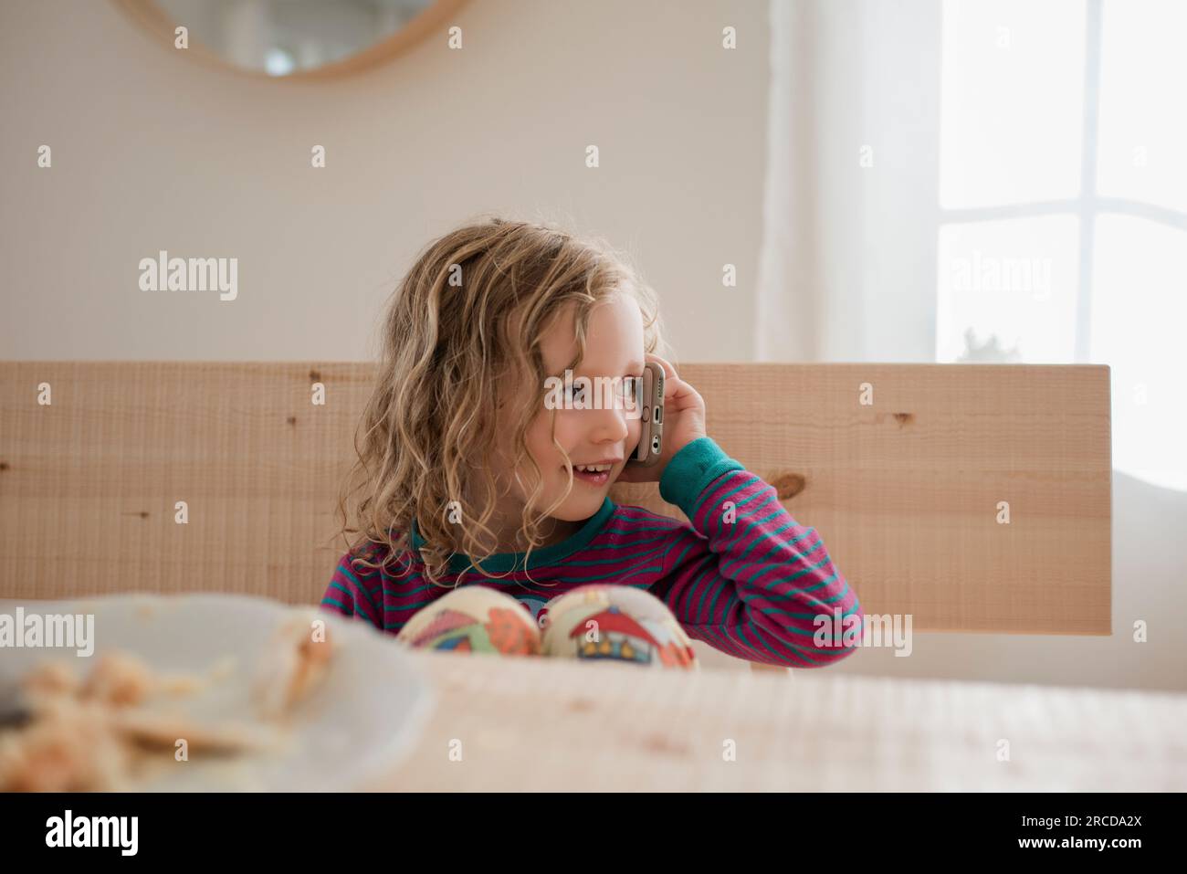 Porträt eines jungen Mädchens, das zu Hause mit einem Handy saß Stockfoto