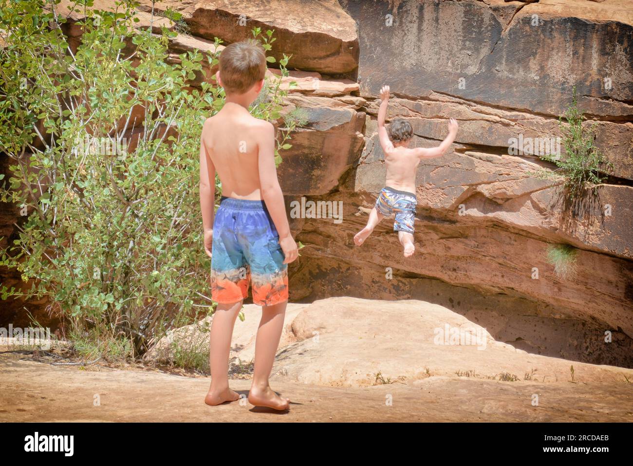 Kleiner Junge springt von der Klippe (von der Kamera weg) in der Nähe von Moab, UT Stockfoto