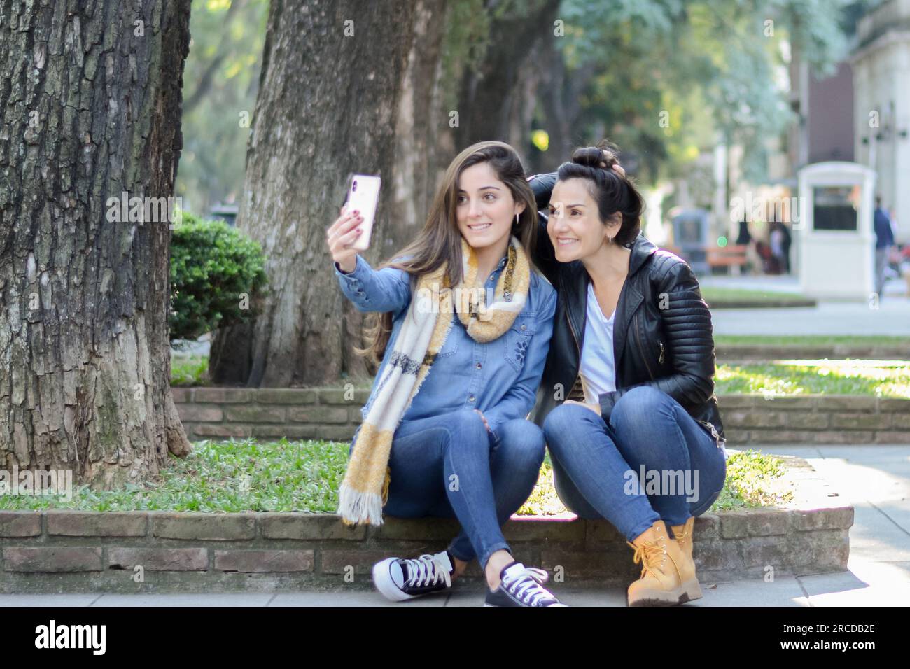 Frauen, die auf der Straße sitzen und ein Selfie machen Stockfoto