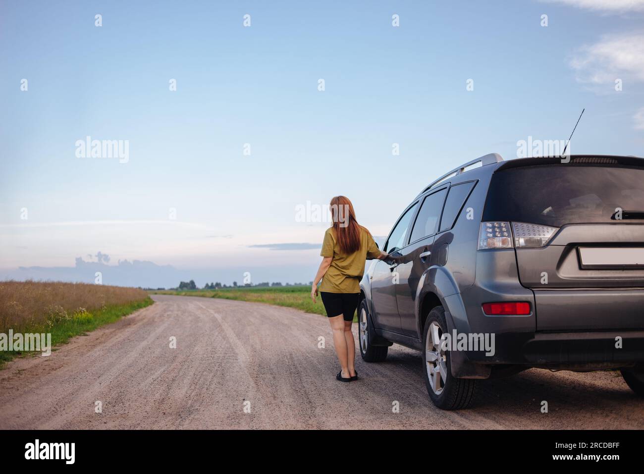 Ein Mädchen auf einem Roadtrip sieht sich die wunderschöne Landschaft neben dem Auto an Stockfoto