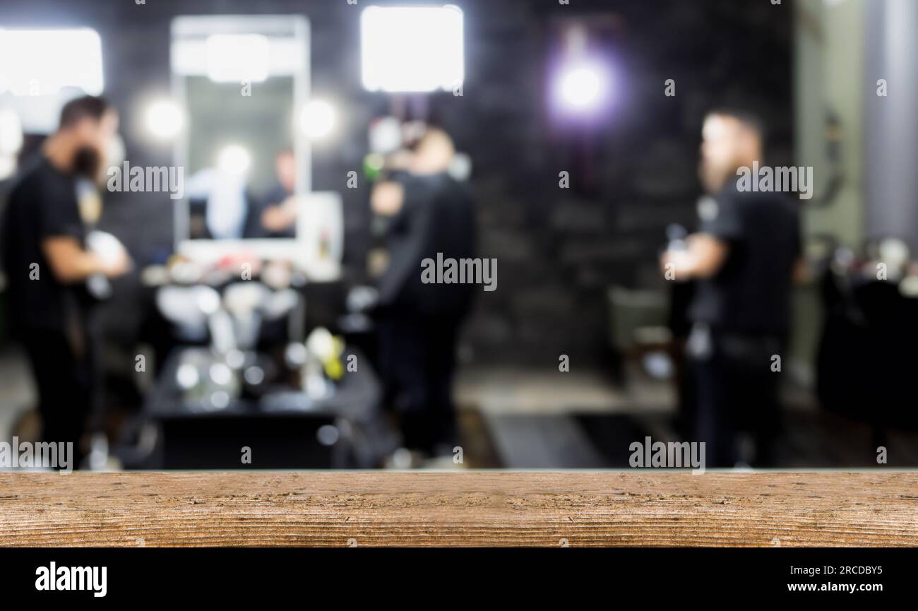 Unscharfe Sicht auf den Friseursalon, Holztisch im Vordergrund. Platz leer für Werbung und Dekoration. Stockfoto