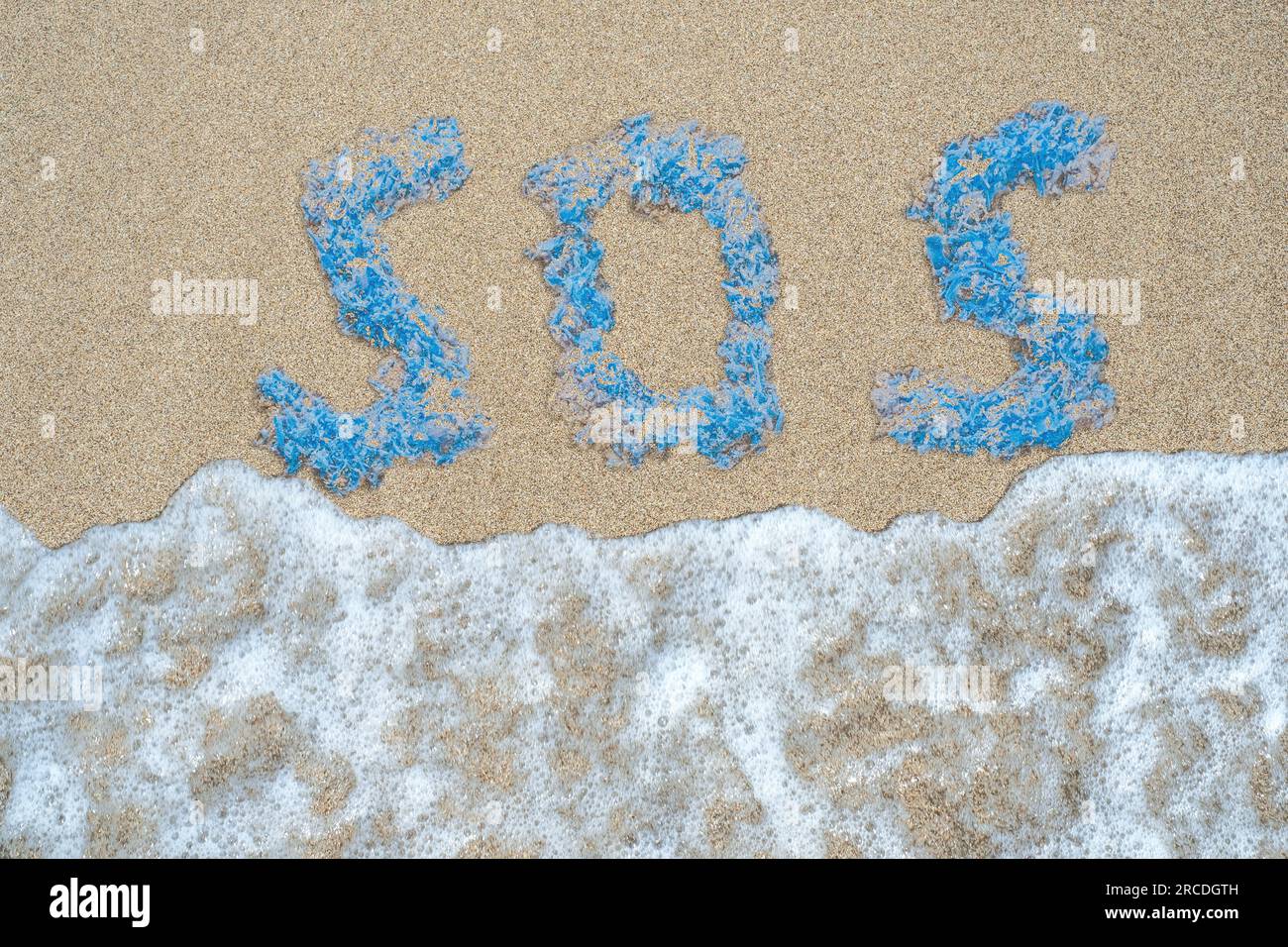 Das Wort SOS besteht aus Plastikteilen, die von der Welle an einem Sandstrand weggespült werden. Draufsicht. Helfen Sie dem Planeten. Rette die Ozeane. Stockfoto