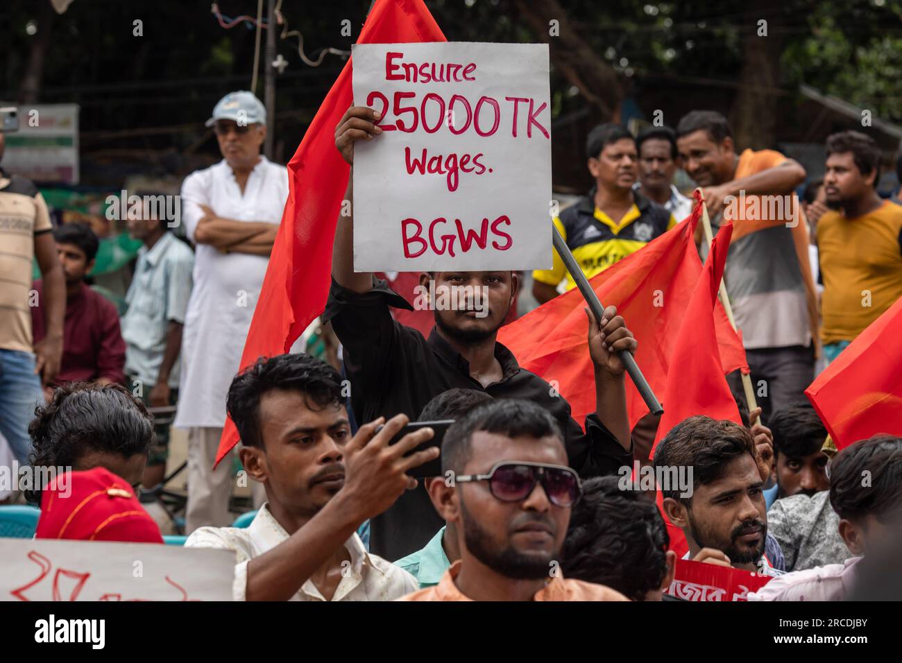Dhaka, Bangladesch. 14. Juli 2023. Ein Protestteilnehmer hält während der Demonstration ein Plakat, auf dem seine Meinung zum Ausdruck kommt. Bangladesche Bekleidungsarbeiter protestieren und fordern eine Erhöhung des Mindestlohns von 25.000 BDT (230 USD) für Arbeitnehmer, da die steil ansteigende Inflation die Arbeiter in Schwierigkeiten bringt. (Foto: Sazzad Hossain/SOPA Images/Sipa USA) Guthaben: SIPA USA/Alamy Live News Stockfoto