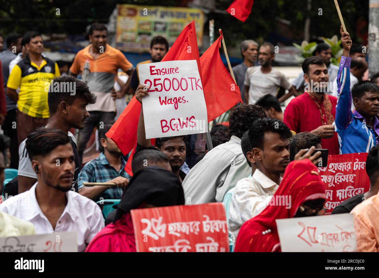 Dhaka, Bangladesch. 14. Juli 2023. Demonstranten halten während der Demonstration Plakate, auf denen ihre Meinung zum Ausdruck gebracht wird. Bangladesche Bekleidungsarbeiter protestieren und fordern eine Erhöhung des Mindestlohns von 25.000 BDT (230 USD) für Arbeitnehmer, da die steil ansteigende Inflation die Arbeiter in Schwierigkeiten bringt. (Foto: Sazzad Hossain/SOPA Images/Sipa USA) Guthaben: SIPA USA/Alamy Live News Stockfoto