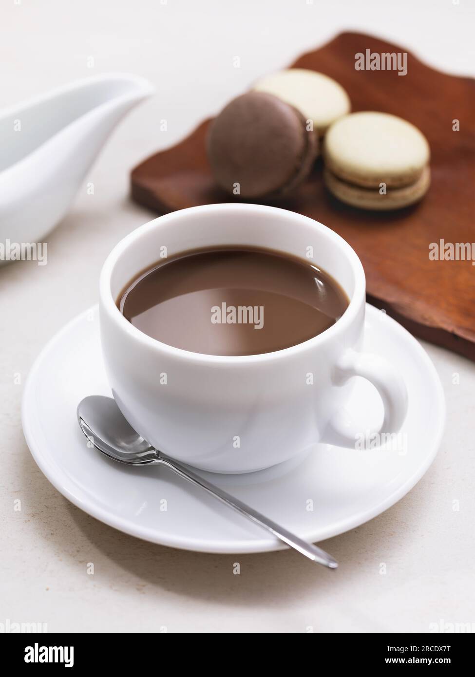 Cappuccino in einen weißen Keramikbecher gegossen, Frühstück mit Makronen Stockfoto