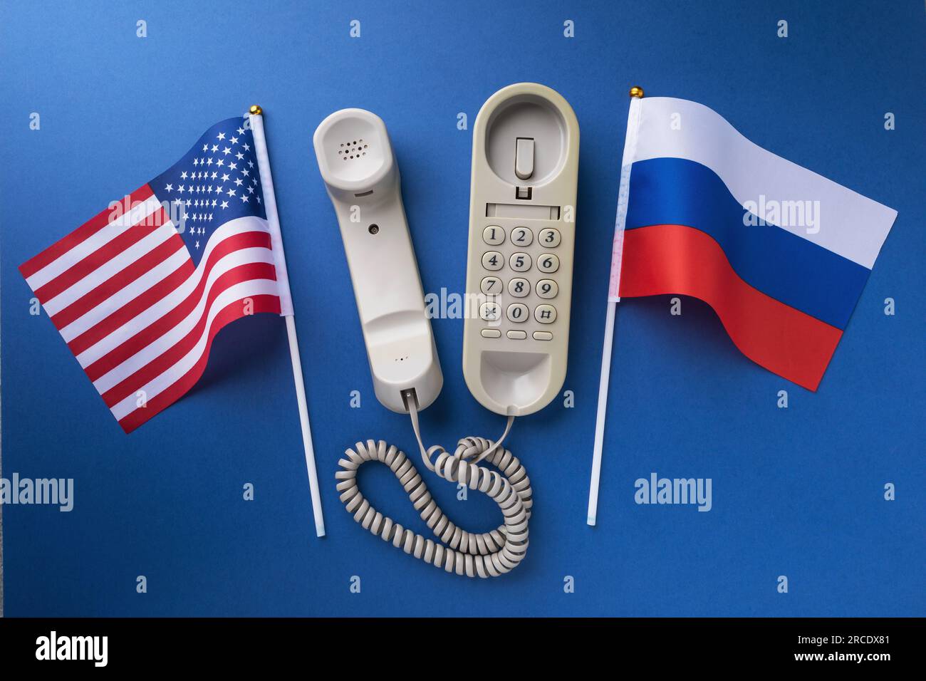 Altes Telefon und zwei Flaggen auf blauem Hintergrund, ein Konzept zum Thema Telefongespräche zwischen den USA und Russland Stockfoto