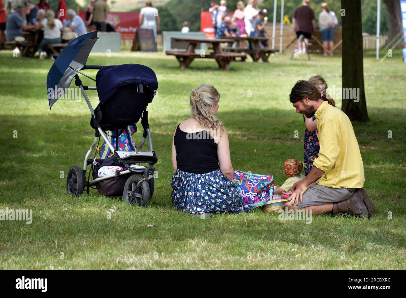Junge Familie sitzt im Schatten auf dem Landfest suffolk england Stockfoto