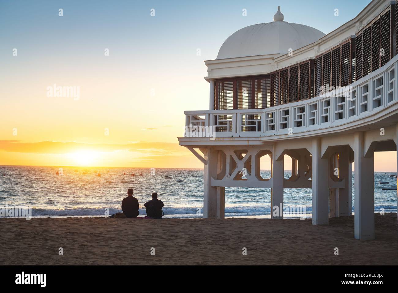 Balneario de la Palma Gebäude am Strand La Caleta bei Sonnenuntergang - Cadiz, Andalusien, Spanien Stockfoto