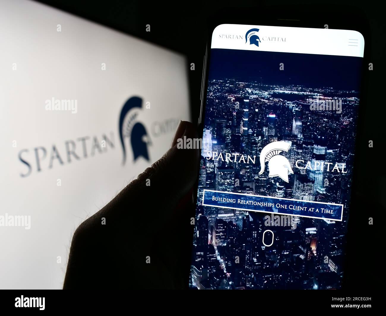 Person, die ein Mobiltelefon mit der Website des US-Unternehmens Spartan Capital Securities LLC auf dem Bildschirm vor dem Logo hält. Konzentrieren Sie sich auf die Mitte des Telefondisplays. Stockfoto