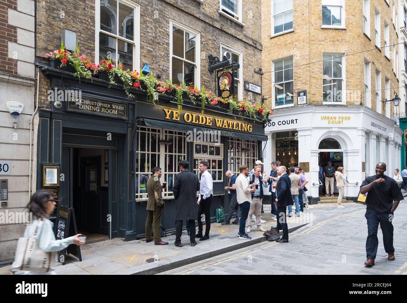 Leute unterwegs zur Mittagszeit. Gruppen von Männern stehen und trinken vor dem Ye Olde Watling Pub. Watling Street, City of London, England, Großbritannien Stockfoto