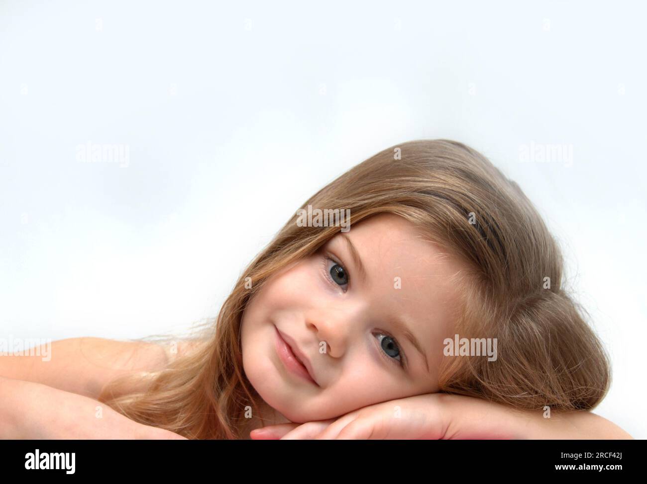 Schönes kleines Mädchen, mit langen Haaren, auf den Armen und Tagträumen. Stockfoto