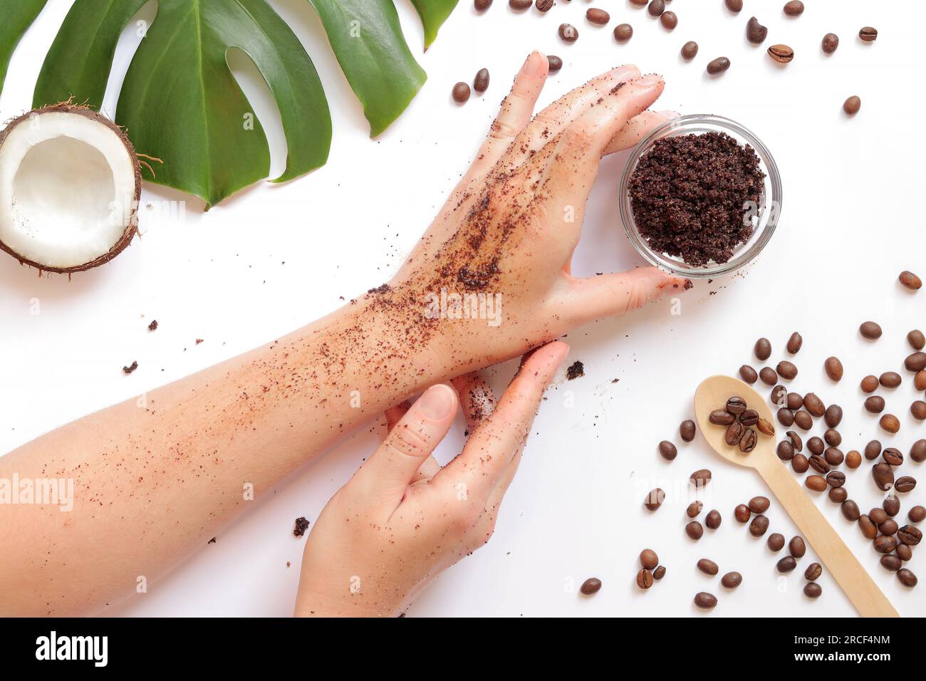 Weibliche Hände mit natürlichem, hausgemachtem Kaffeespeeling auf weißem Hintergrund, Zutaten in der Nähe, Draufsicht. Spa-Behandlung. Spa-Konzept für Selbstpflege Stockfoto