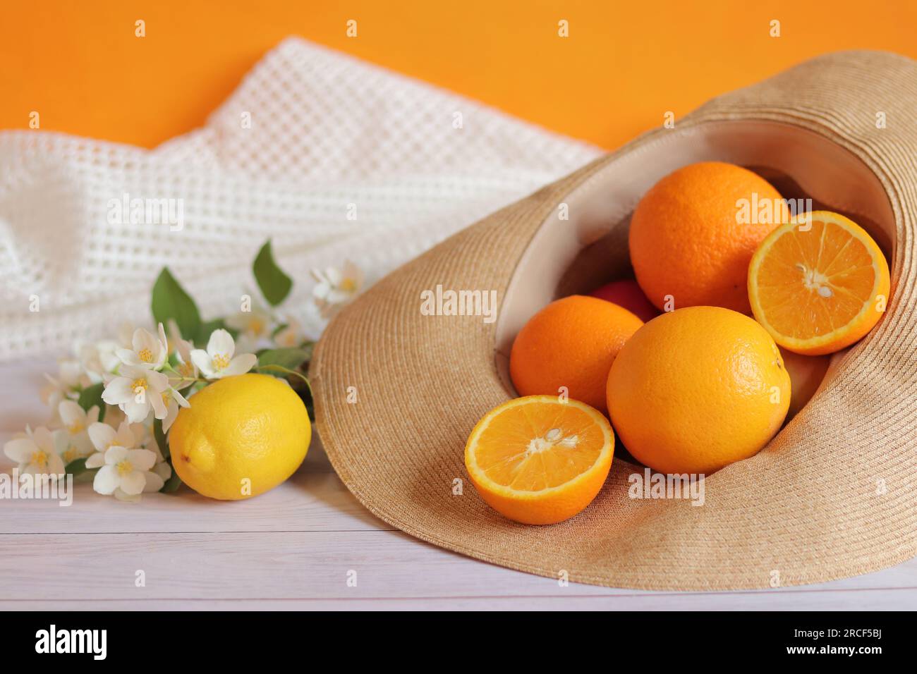 Reife Orangen in einem Sommerhut. Zitrusernte im Hut. Nützliche saisonale Produkte mit vielen Vitaminen. Vitamin-C-reiche Lebensmittel. Kopierraum Stockfoto