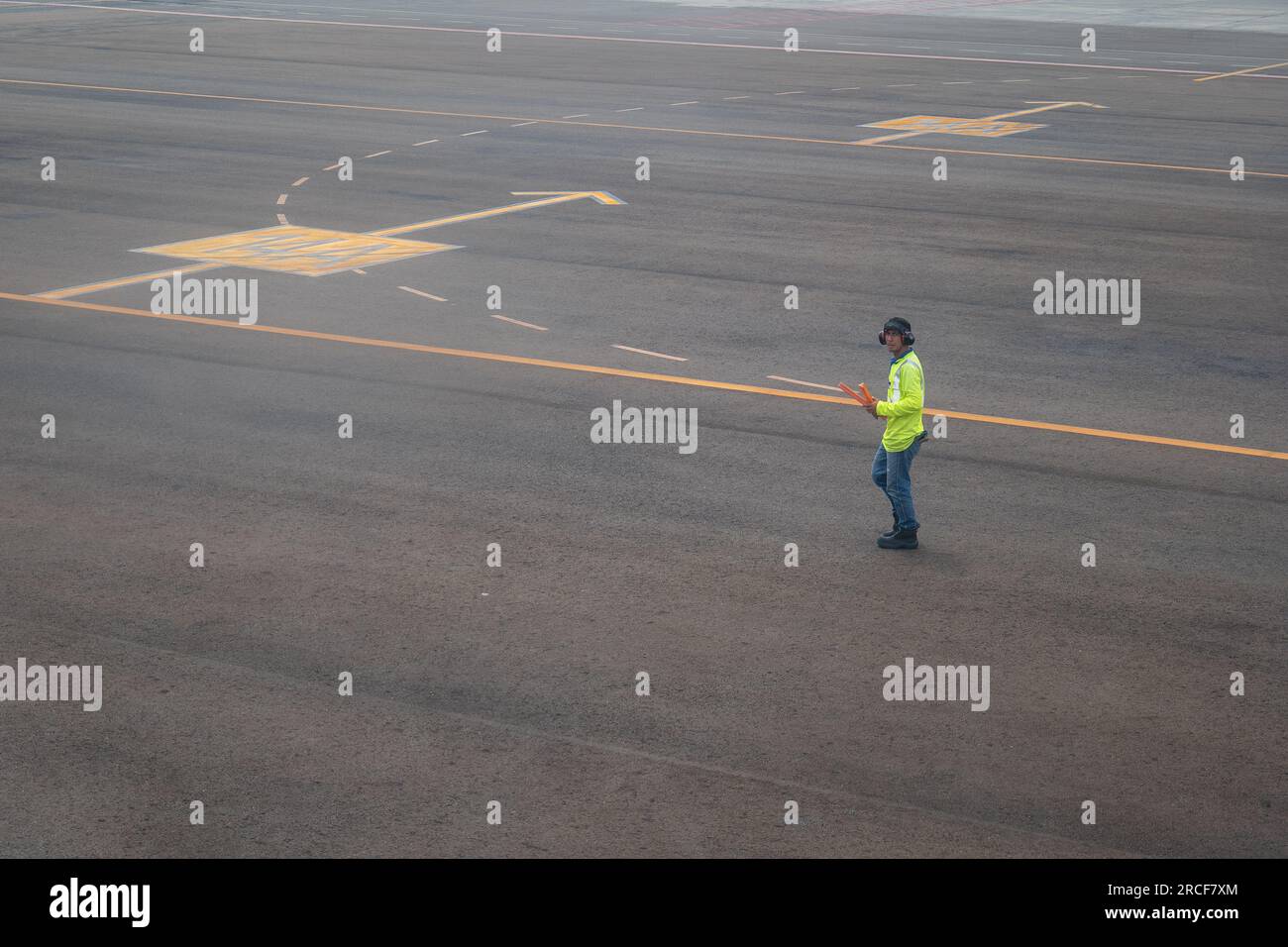 Medellin, Antioquia, Kolumbien - 23. Oktober 2022: Männlicher Fluglotse mit fluoreszierender gelber Weste und blauen Jeans starrt auf das Lens Walking D Stockfoto