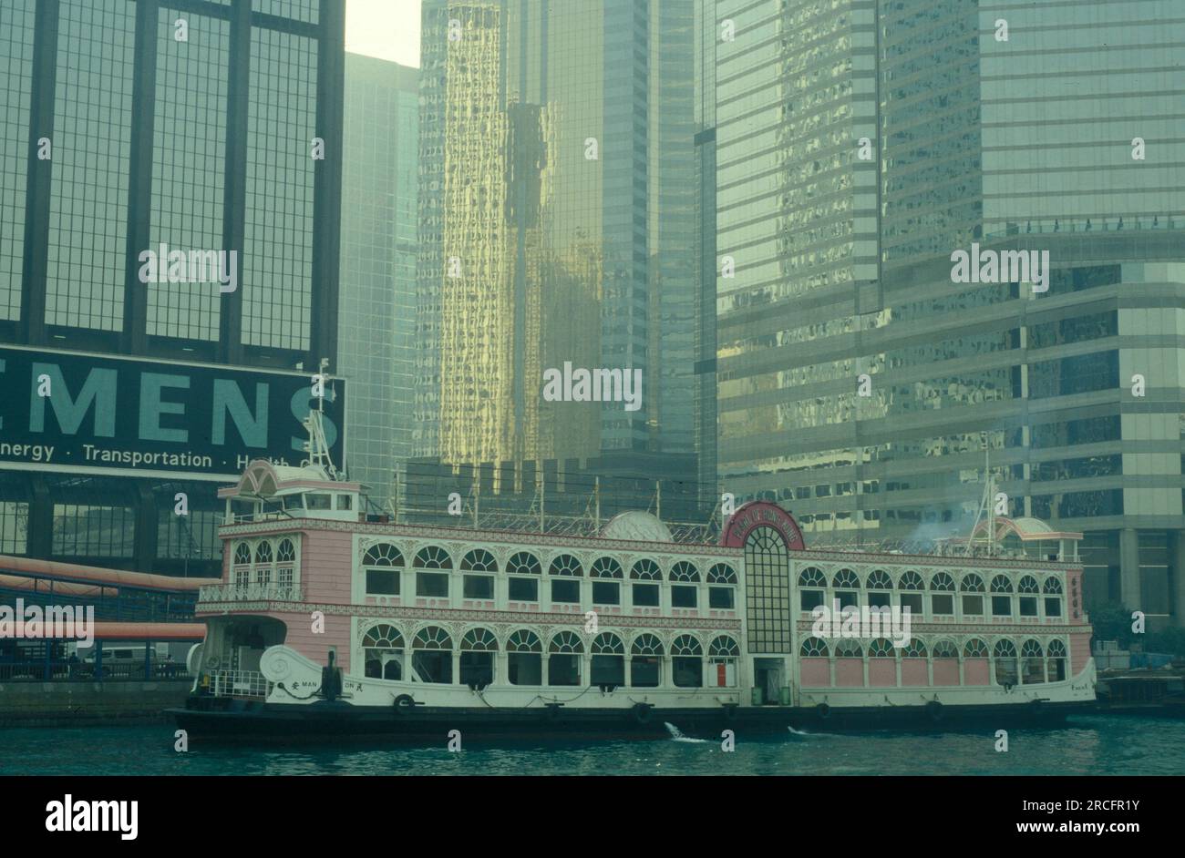 Ein schwimmendes Restaurantboot vor der Skyline von Zentral-Hongkong vom Aussichtspunkt Kowloon in der Stadt Hongkong in Hongkong. China, Hongkong Stockfoto