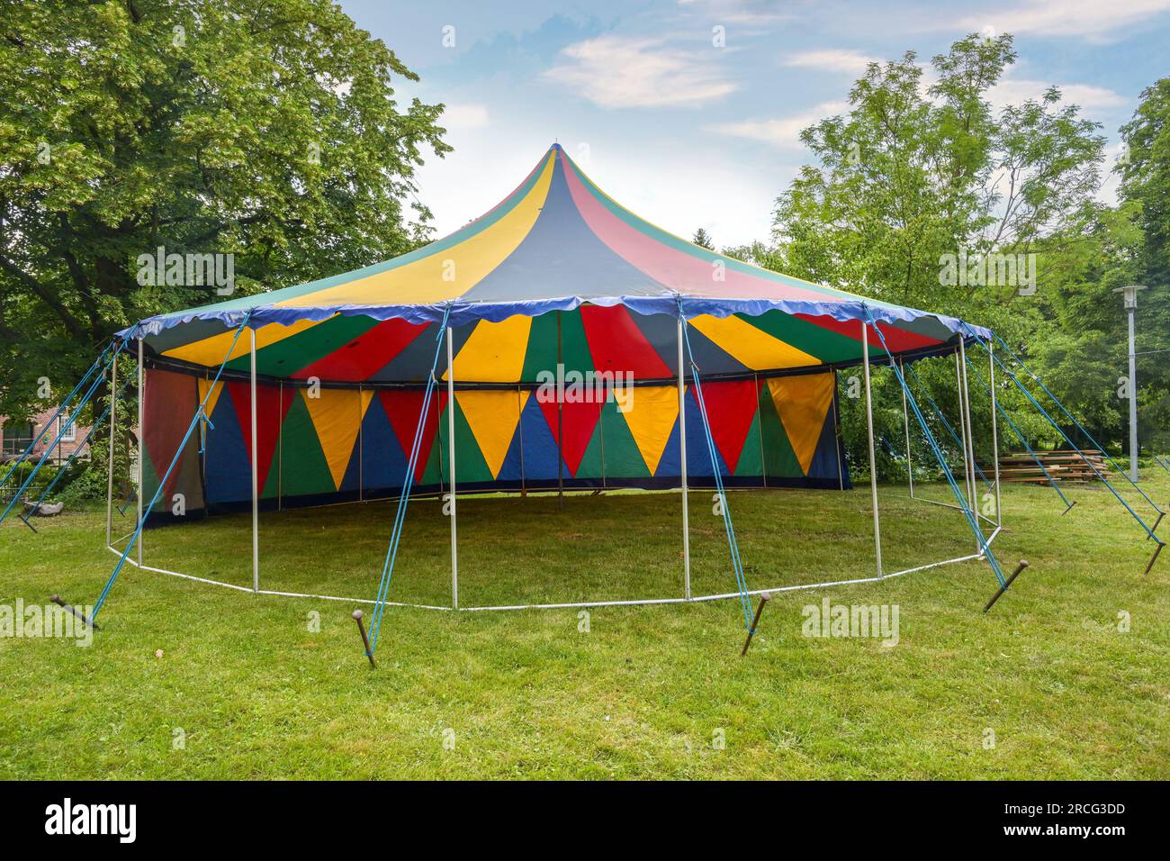 Kleines farbenfrohes Zirkuszelt mit einer Stange, die auf einer Wiese halb offen steht, für eine Sommerparty oder ein Festival, Kopierbereich, ausgewählter Fokus Stockfoto